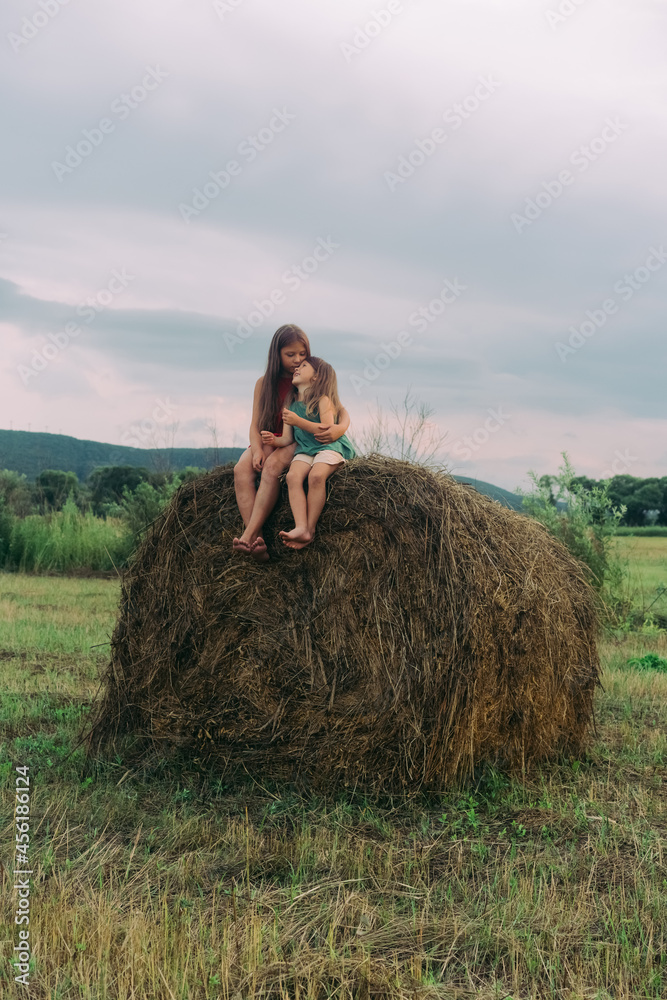 two little sisters sit on a haystack. High quality photo two little sisters sit on a haystack. High quality photo