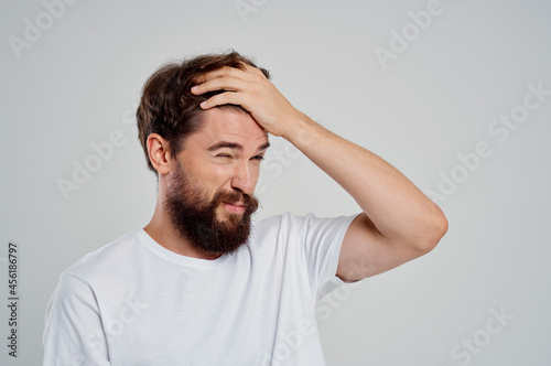 man holding his head pain stress emotions light background