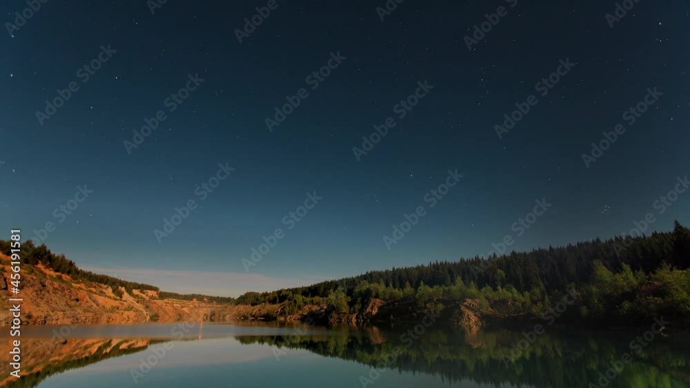 Timelapse landscape with a lake, in the sky above the lake there are stars. Summer lake next to a cliff against the backdrop of a starry evening sky. Timelapse landscape with a lake, in the sky above the lake there are stars. Summer lake next to a cliff against the backdrop of a starry evening sky.