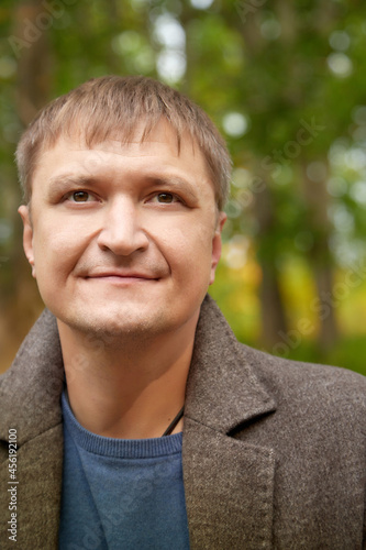 Portrait of a serious man in nature with a green background in the forest or in the park