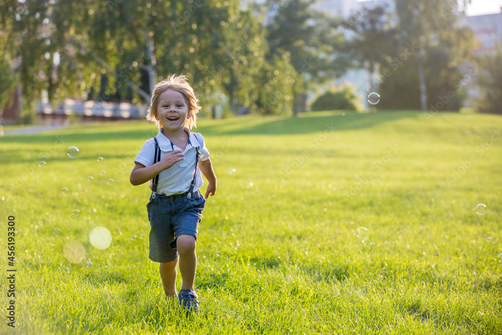 Cute preschool blond child, playing in the park on sunset, summertime Cute preschool blond child, playing in the park on sunset, summertime