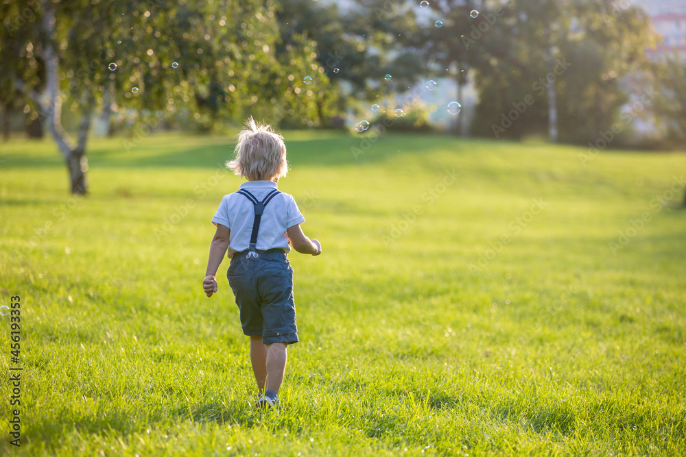 Cute preschool blond child, playing in the park on sunset, summertime Cute preschool blond child, playing in the park on sunset, summertime