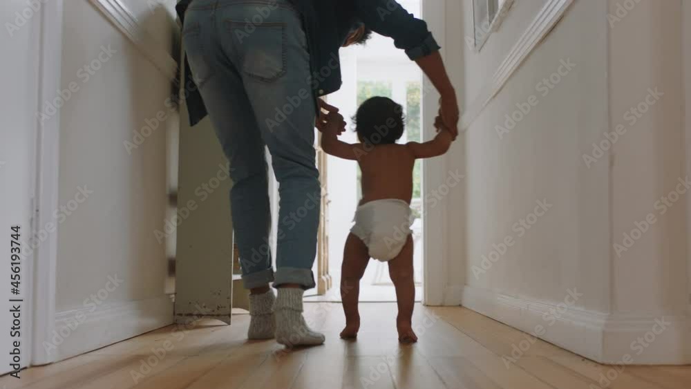 baby taking first steps learning to walk with mother and father teaching toddler at home enjoying parenthood