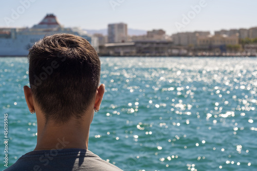 View of a teenager in the port of Malaga looking at the sea