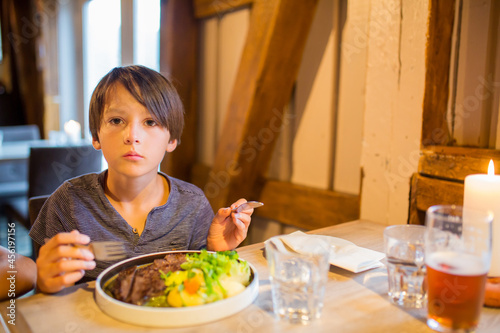 Preschool child  cute boy  eating lamb meat in a restaurant  cozy atmosphere  local small restaurant in Tromso