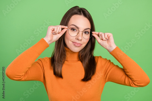 Portrait of attractive cheery brainy brown-haired girl wearing touching specs healthy life isolated over green color background © deagreez