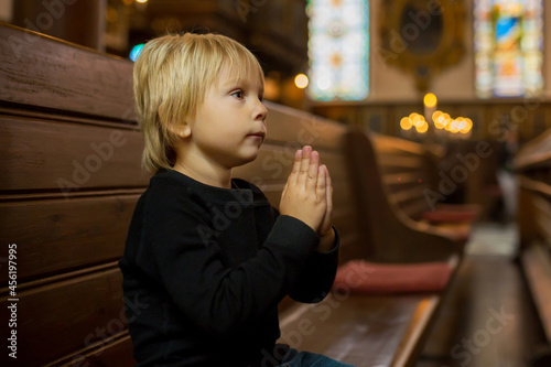 Little child, boy, praying in church, cathedrale in Stockholm, Sweden