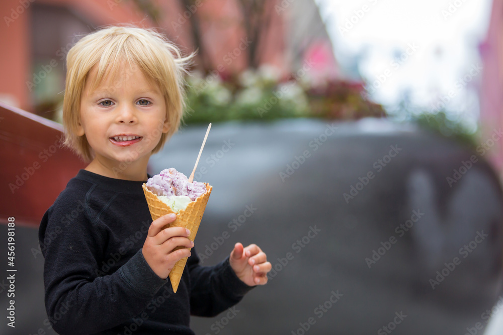 Fototapeta premium Cute blond child with black shirt, eating churros on the street in the city of Stockhlom, sweet desert sold on every corner