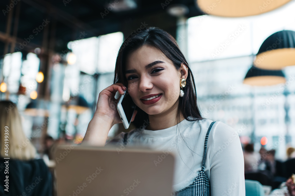 Smiling female speaking on smartphone in cafe in daytime Smiling female speaking on smartphone in cafe in daytime