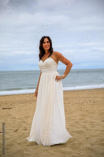 Glückliche junge Frau im Hochzeitskleid am Meer 