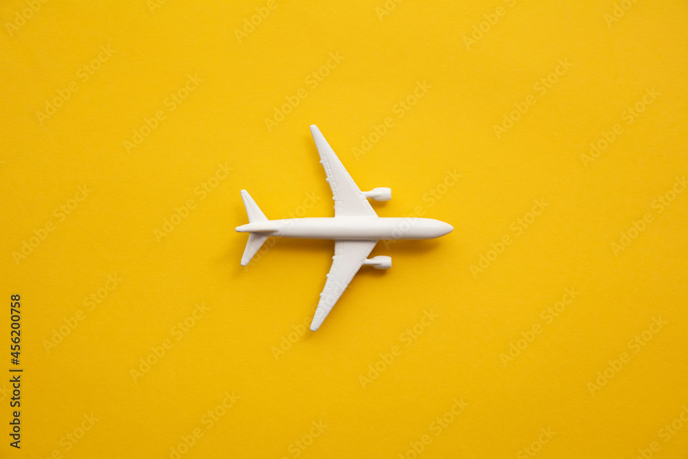 White passenger airplane on a summer yellow background. Travel and vacation background