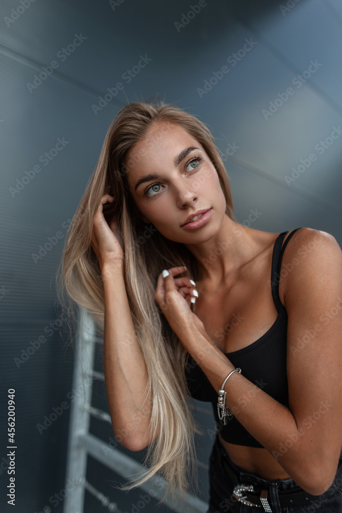 © alones - Beauty portrait of fashion sexual caucasian woman model with pretty face in black tank top with silver bracelet near a black metal building in the city © alones - Beauty portrait of fashion sexual caucasian woman model with pretty face in black tank top with silver bracelet near a black metal building in the city