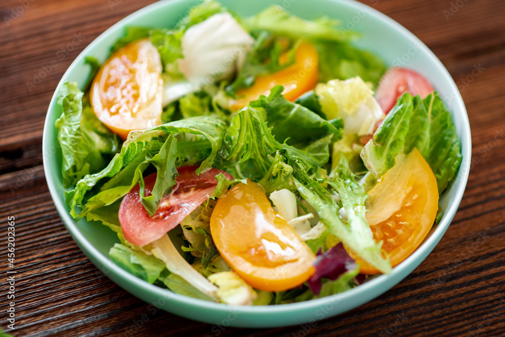 Healthy salad of fresh vegetables, herbs and tomatoes on a wooden background. Healthy salad of fresh vegetables, herbs and tomatoes on a wooden background.