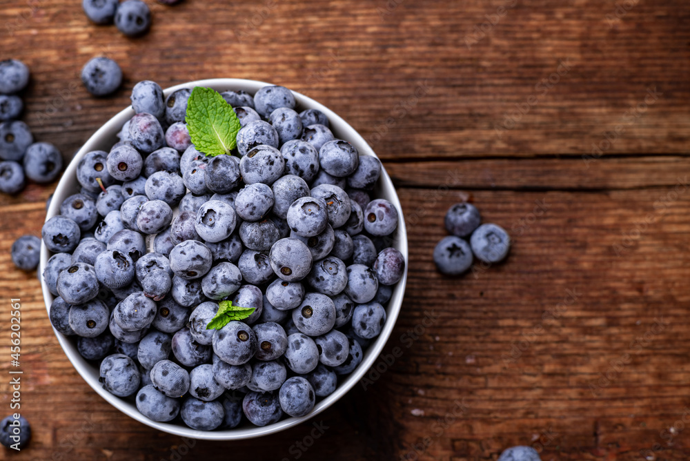 Fresh blueberries in a bowl on a brown wooden background. Fresh blueberries in a bowl on a brown wooden background.
