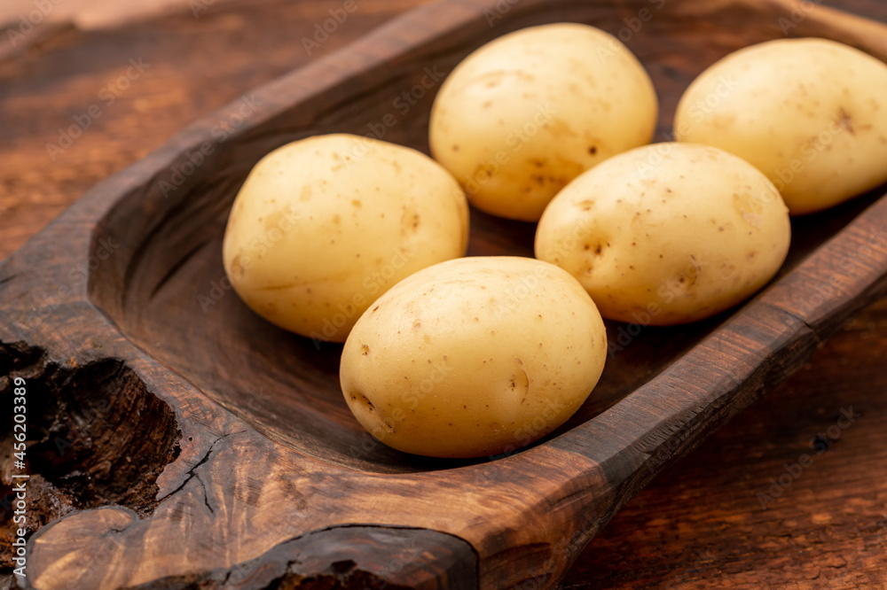 Tubers of large young potatoes on a wooden background. Tubers of large young potatoes on a wooden background.