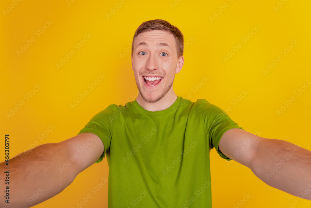 Portrait of young cheerful man happy positive smile taking a selfie isolated over yellow color background Portrait of young cheerful man happy positive smile taking a selfie isolated over yellow color background