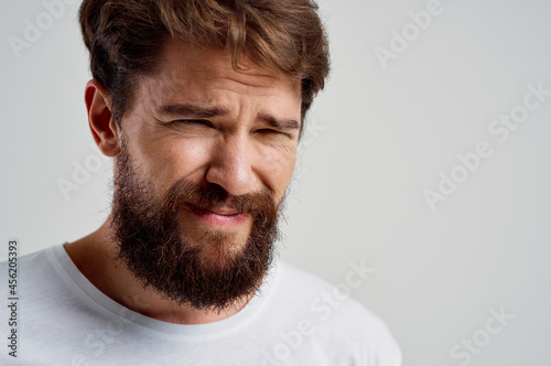 bearded man in a white t-shirt headache migraine problems isolated background
