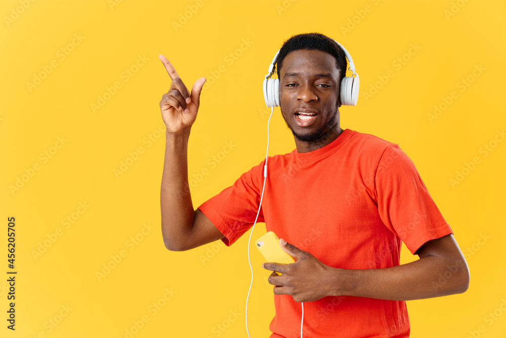 African man wearing headphones music studio yellow background