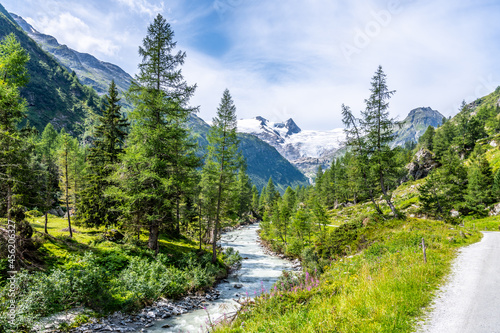 Idyllic alpine landscape with Grossvenediger Mountain. Small mountain creek in Gschloess Valley. Hohe Tauern National Park, Austrian Alps photo