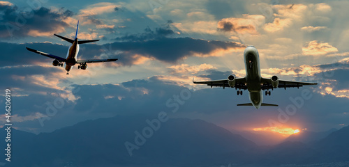 Colorful sunrise with clouds landing and taken off airplanes, concept of travels and vacations