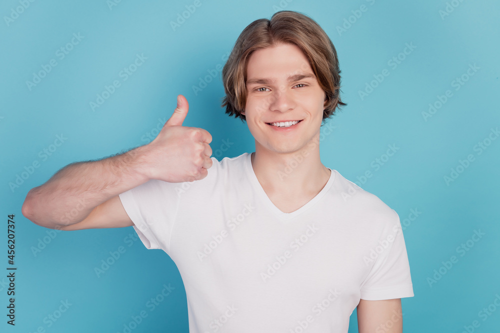 Happy man with beaming smile showing thumb up isolated on blue background Happy man with beaming smile showing thumb up isolated on blue background