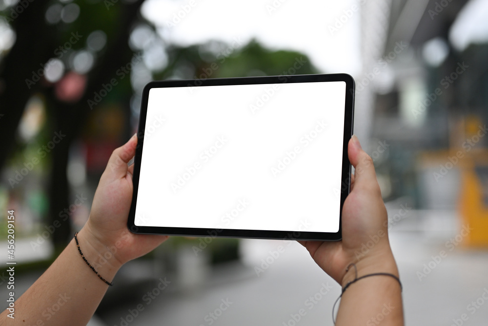 Cropped image of the hand using a white blank screen digital tablet in the park. Cropped image of the hand using a white blank screen digital tablet in the park.
