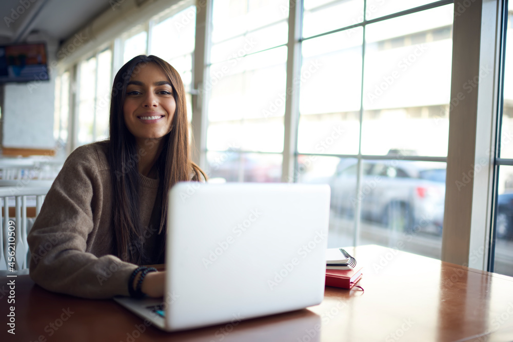 Portrait of cheerful female IT professional with modern laptop computer smiling at camera during distance job in coworking space, happy Caucasian woman with netbook enjoying freelance lifestyle Portrait of cheerful female IT professional with modern laptop computer smiling at camera during distance job in coworking space, happy Caucasian woman with netbook enjoying freelance lifestyle