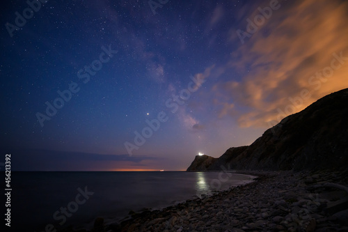 Amazing view with starry sky after sunset over rocky Black sea coast and cape Emine with the lighthouse, Bulgaria