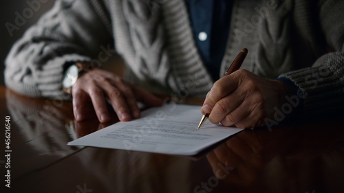 Elderly man hands working document at home. Old male arms making marks contract