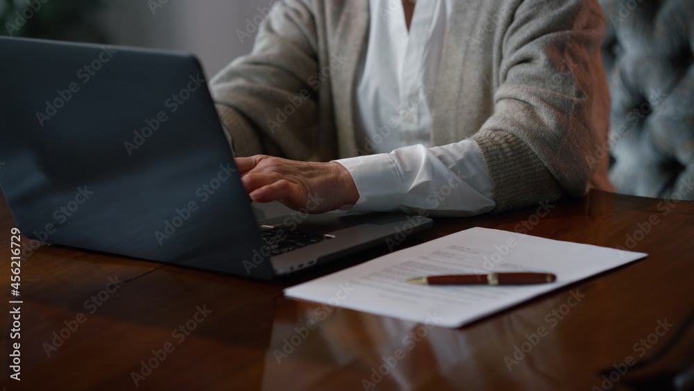 Senior business woman using laptop at home workplace. senior woman hands Senior business woman using laptop at home workplace. senior woman hands