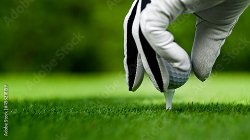 Male hands in a white glove put a golf ball