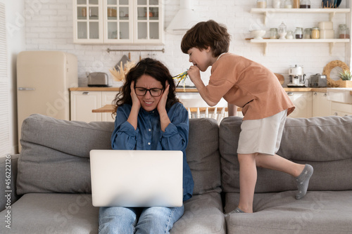 Foto Mother working from home cover ears with hands to protect from loud noises from
