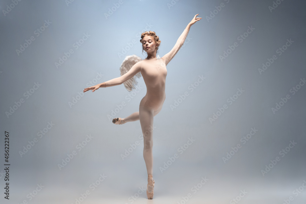 Young and graceful ballet dancer, ballerina dancing isolated on white gray studio background. Art, motion, action, flexibility, inspiration concept. - obrazy, fototapety, plakaty 