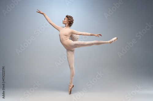 Obraz na plátně Young and graceful ballet dancer, ballerina dancing isolated on white gray studio background