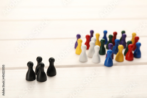 Canvas Print Colorful game pieces on white wooden table. Racism concept