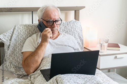 senior man male in bed working home office holding laptop Jobs for Retirees