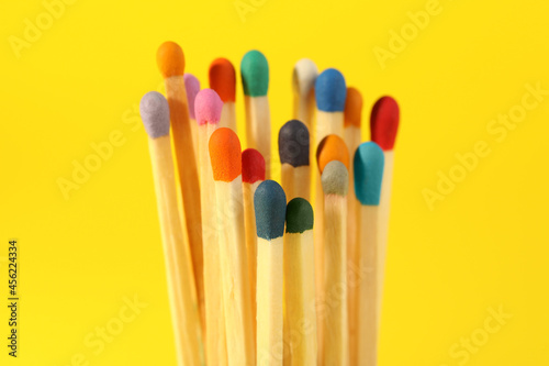 Matches with colorful heads on yellow background, closeup