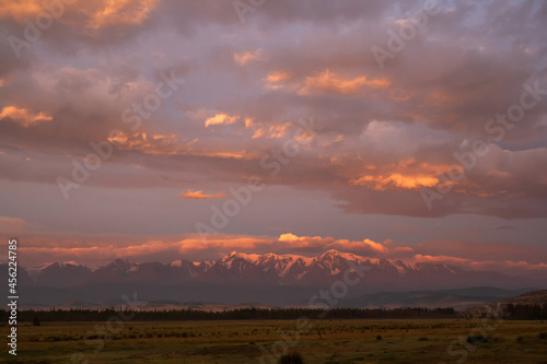 Morning in the mountains, pink dawn in the high mountains in the snow, cloudy mountain landscape
