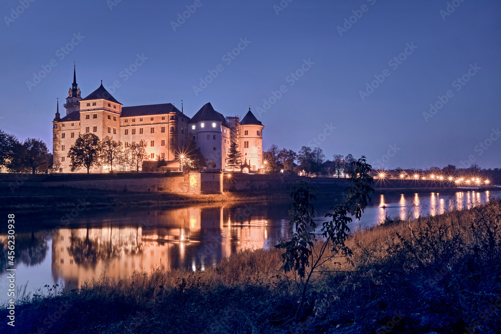 Das beleuchtete Schloss Hartenfels am Ufer der Elbe in Torgau.