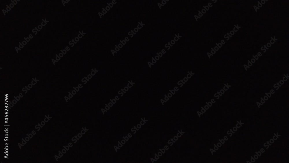 Footage of fast train passing by at night. Way locomotive and wagons, going nightly in dark. Blurry yellow windows, lights flash as the train goes by in the darkness.