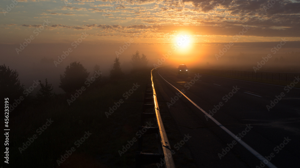 The road going into fog towards the rising sun