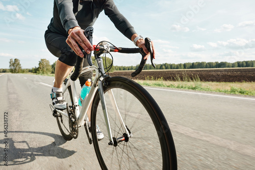 Close-up of cyclist in sports clothing riding a bike on a country road