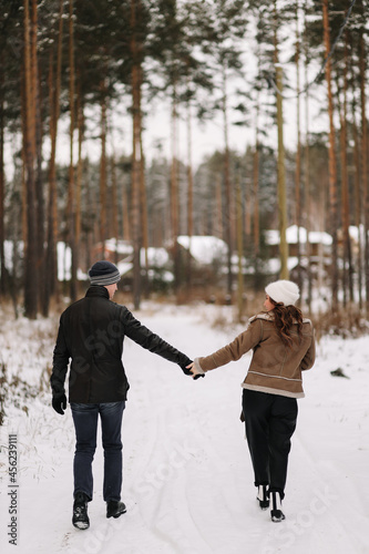 A man and a woman in love in outerwear are having fun hugging walking outside the city among the trees in the winter forest during the Christmas holidays  a selective focus