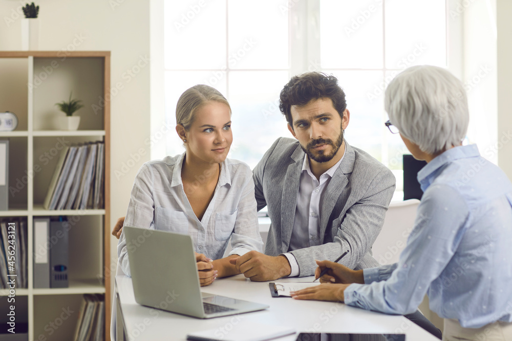 Female specialist in lending and financial assistance to young families advises the couple. Family listens to a female banking agent when deciding to buy a home or make a financial investment. Female specialist in lending and financial assistance to young families advises the couple. Family listens to a female banking agent when deciding to buy a home or make a financial investment.