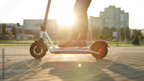 E-scooter rider, man ride sharing or rent personal eco transportation. Male hipster riding an electric scooter road to work the modern way. Fast speed driving electric transport, morning light