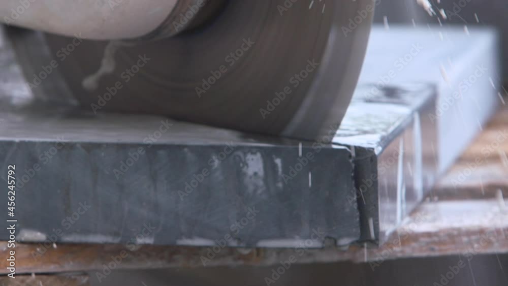 Wet Electric circular saw power tool cutting pavement stone corner slow motion close up