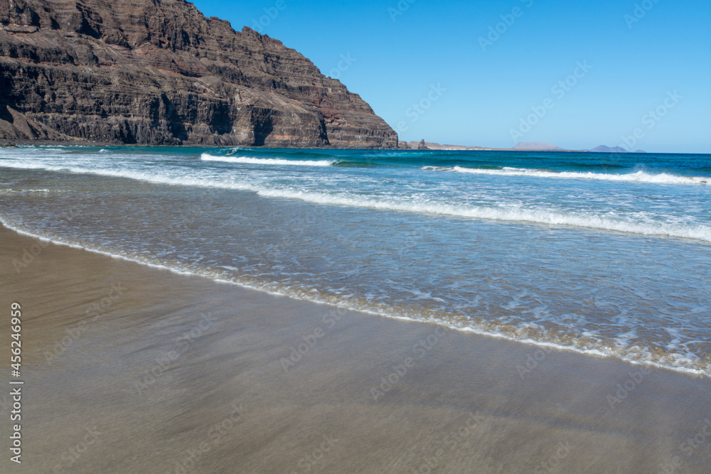 Black lava rocks and water waves of Atlantic ocean, nature landscape on Lanzarote, Canary islands, Spain