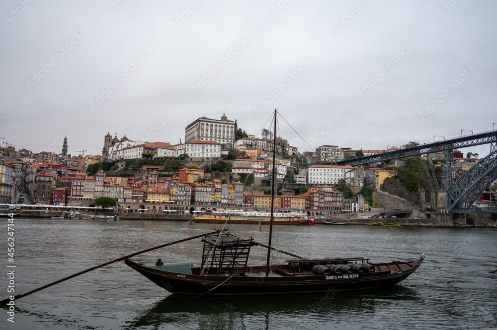 Obraz premium Porto, Portugal, October 31,2020. View from Vila Nova de Gaia on port makers boats and colorful old houses on hill in old part of city. Embankment of Douro river in rainy day