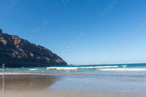 Black lava rocks and water waves of Atlantic ocean, nature landscape on Lanzarote, Canary islands, Spain