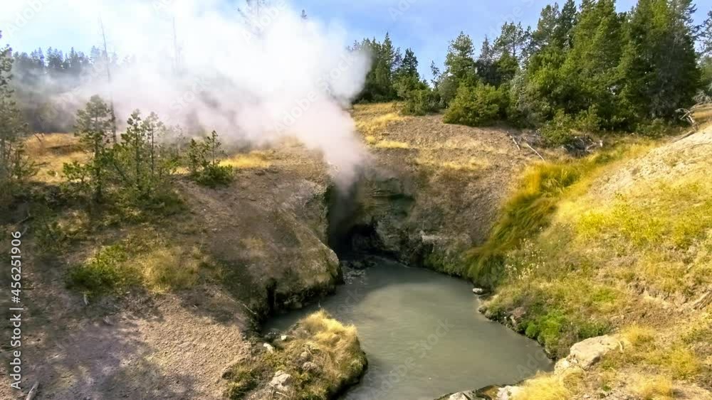 Dragons Mouth Spring in Yellowstone National Park, WY. Boiling water rolls out of a small cave-like opening, steam billowing from within. Bizarre noises emit from the opening. Dragons Mouth Spring in Yellowstone National Park, WY. Boiling water rolls out of a small cave-like opening, steam billowing from within. Bizarre noises emit from the opening.